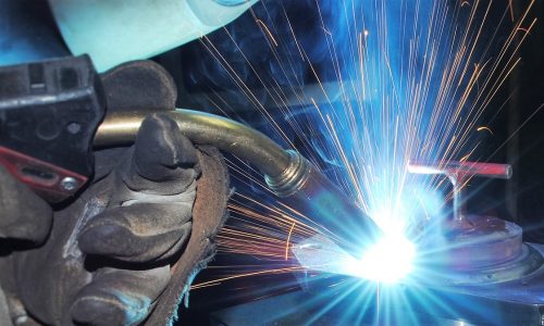 Welding services in Southeastern PA. The image shows a welder working on a metal structure, with sparks flying and protective gear visible, highlighting the welding process in an industrial workshop or construction site.