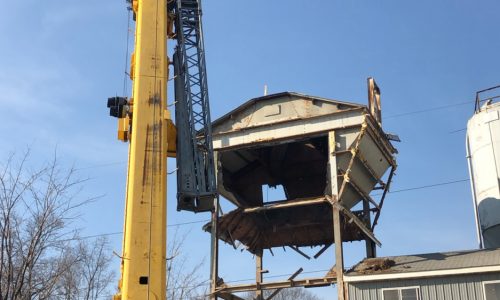 Photo of a tall lift moving large parts around a job site.