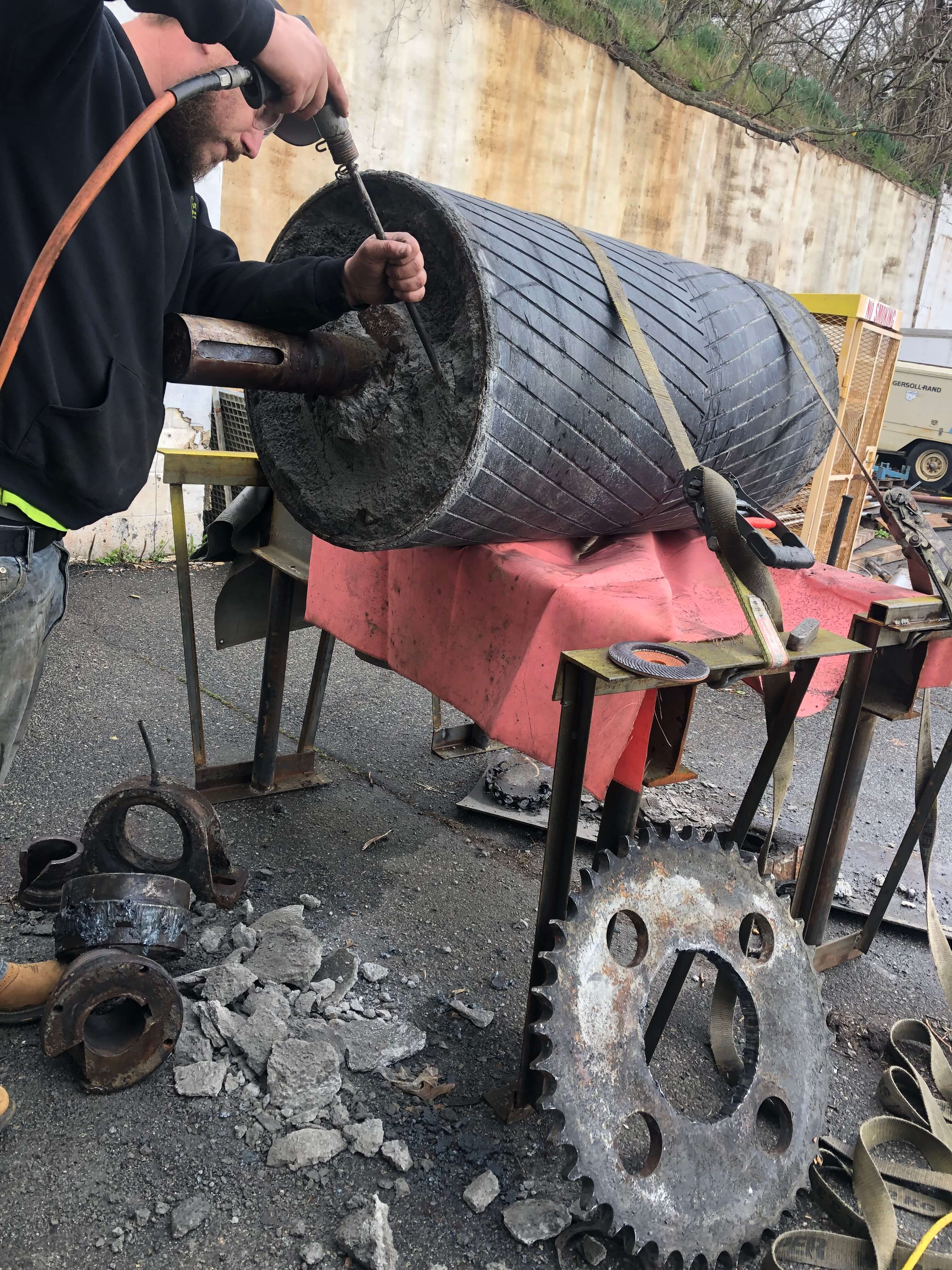 employee reconditioning a massive wheel from a conveyor system